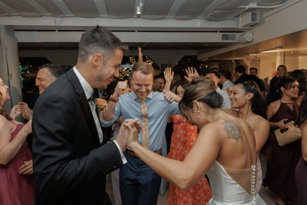 AJ and wedding guests sharing a joyful candid moment during the reception