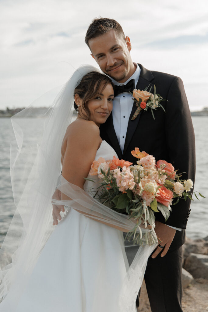 AJ and Janel sharing a joyful moment during waterfront wedding portraits