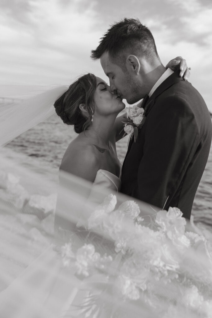 AJ and Janel sharing a kiss during their waterfront wedding portraits