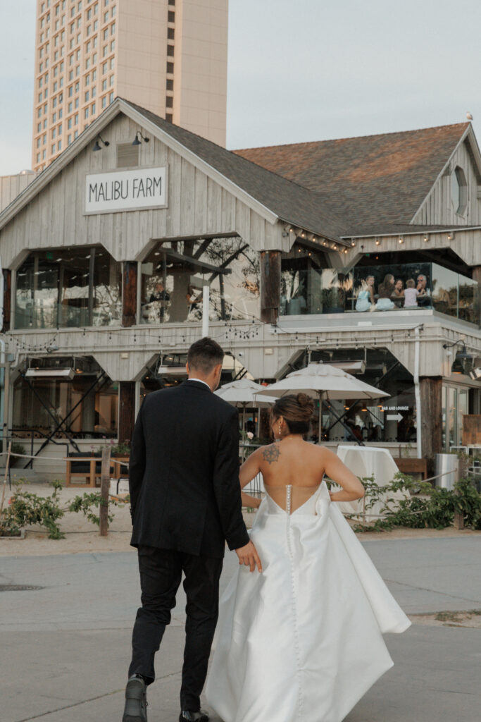 AJ and Janel walking outside Malibu Farm during their wedding celebration