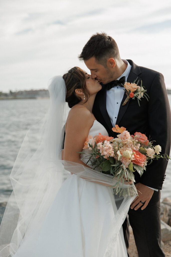 AJ and Janel sharing a kiss beside the water during their Malibu Farm wedding