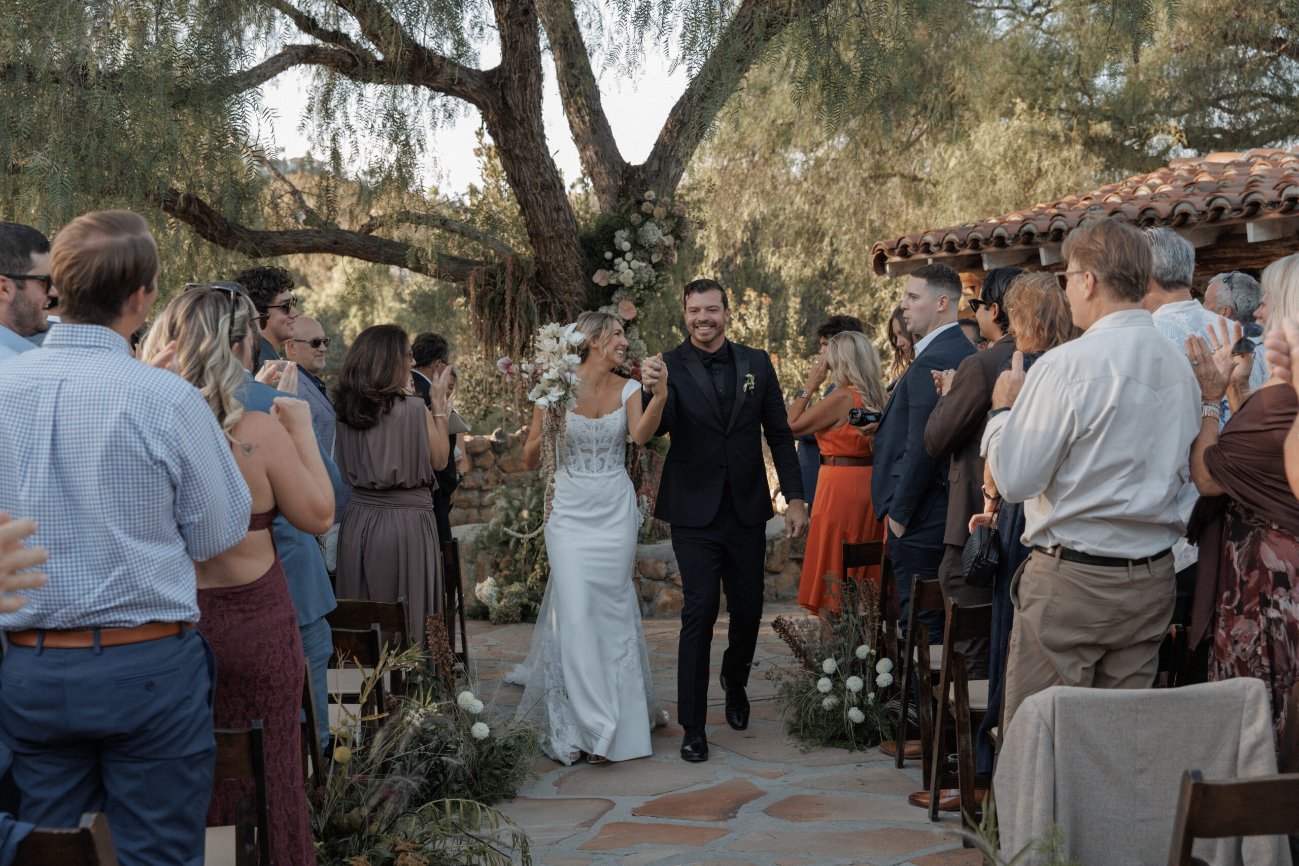 Wedding couple surrounded by family and friends during an outdoor wedding ceremony
